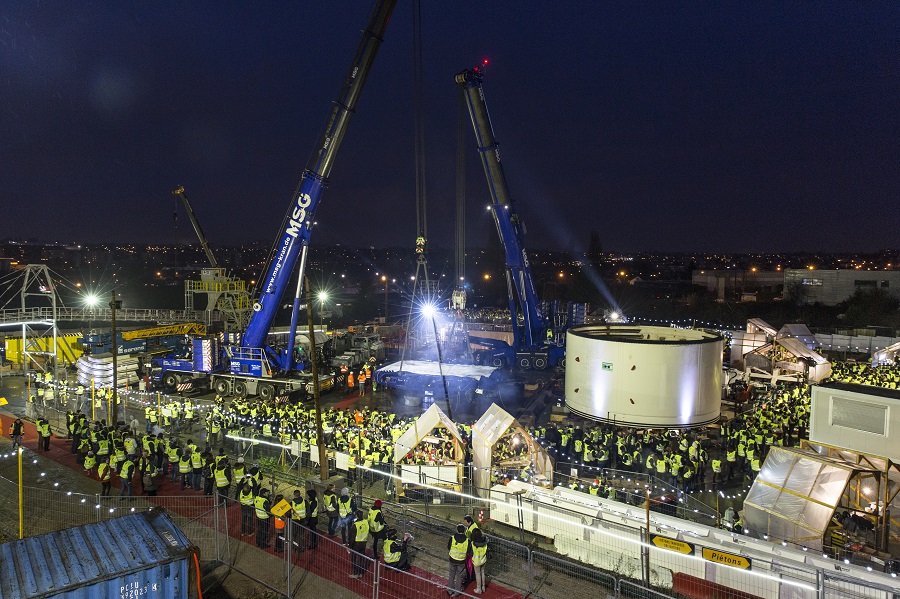 Le public en gilet jaune de chantier, de nuit, observe le lever de la roue de coupe du tunnelier, sur le chantier de Champigny lors du KM3