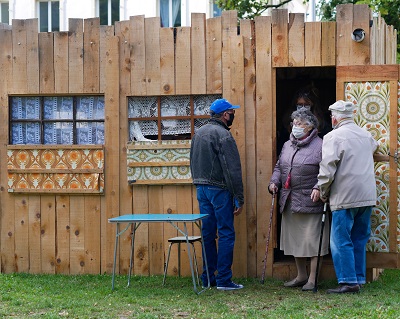 Trois personnes à l’entrée d’un des cabinets en bois dans le cadre du spectacle « Palissades » de la Compagnie Le Phun à Sevran