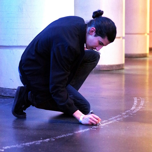 Le designer Eddy Terki en train de tracer des lettres au sol 