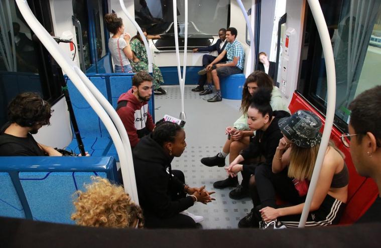 Une dizaine de personnes assises et débout discutent dans une maquette à échelle 1 du nouveau matériel roulant pour le Grand Paris Express