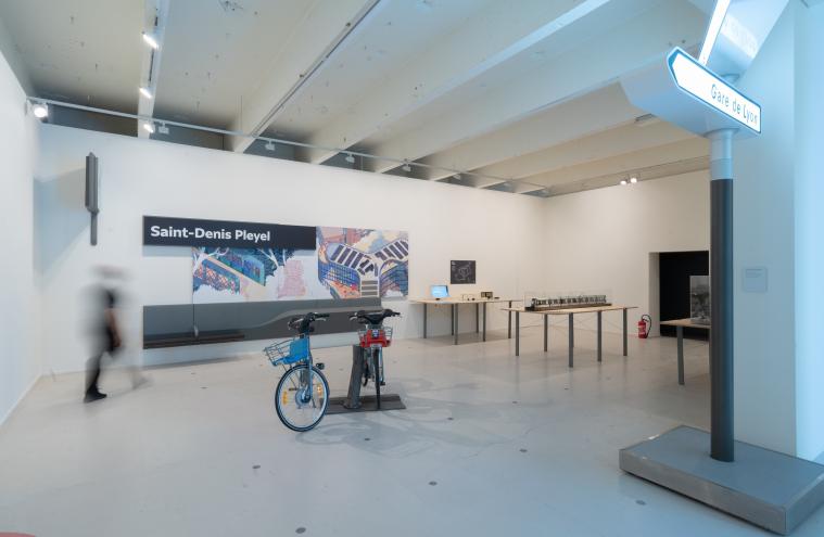 Espace d’exposition des mobiliers et de la signalétique du Grand Paris Express à Lille Métropole 2020 Capitale Mondiale du Design avec des assises, une fresque et le nom de gare