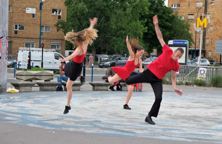 Trois danseurs en rouge et noir dansent devant l’arrêt de métro Fort d’Aubervilliers pendant l’AuberJazz Day
