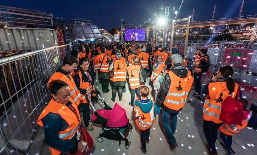 Public en gilets de chantier orange la nuit sur le chantier du puits Mandela à Saint-Denis