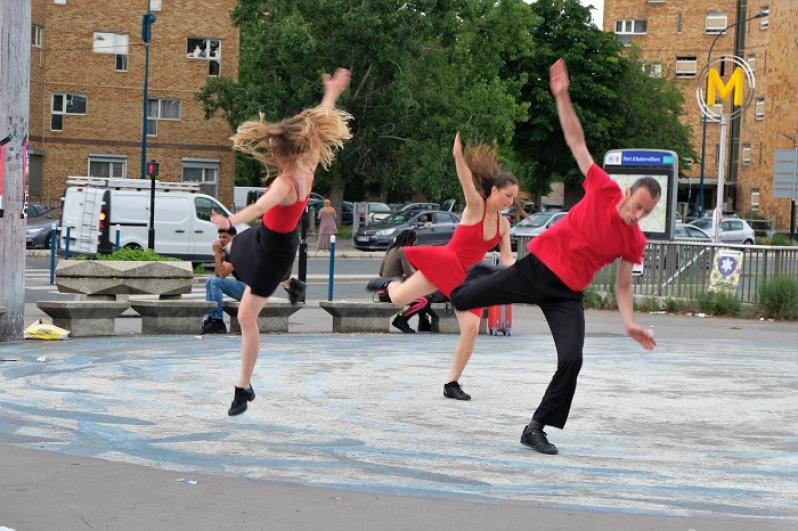 Trois danseurs en rouge et noir dansent devant l’arrêt de métro Fort d’Aubervilliers pendant l’AuberJazz Day