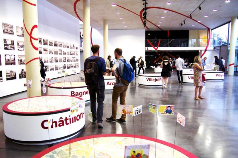 Environ 15 visiteurs dans une des salles de l’exposition « Les passagers du Grand Paris Express », avec des photographies au mur 