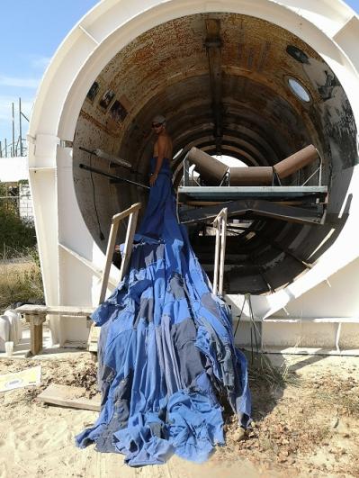 Un engin de chantier en forme de tunnel et un danseur avec un grand tissu, dans le cadre du projet de la Compagnie Tangible à Vitry-sur-Seine